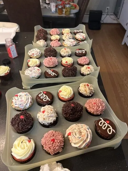 Assorted custom cupcakes in boxes with different frosting colors and toppings