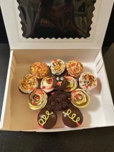 Assorted cupcakes arranged in a bakery box with varied frosting designs